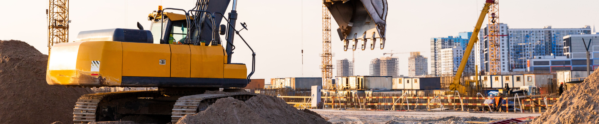 Construction workers reviewing blueprints on-site with a crane in the background, representing ProjectLink's project management solutions for the construction industry.