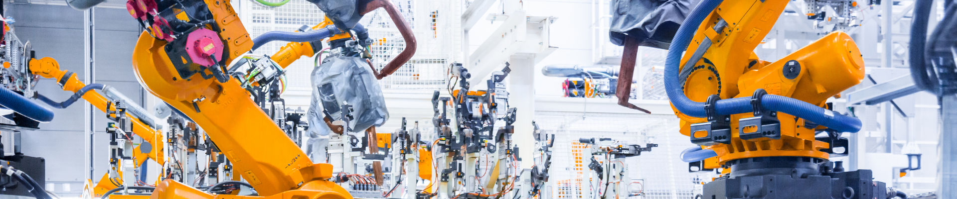 Orange robotic arms operating on an automated factory production line, representing ProjectLink's project management solutions for the manufacturing industry.