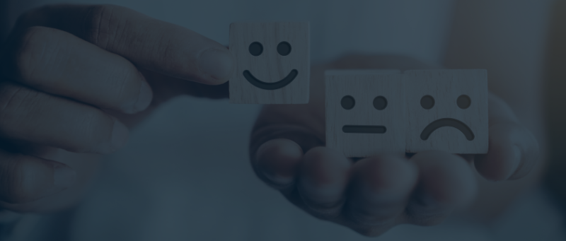 Webiste Blog Banners Hand selecting a smiling wooden emotion block over neutral and sad expression blocks, symbolising emotional intelligence