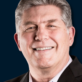Headshot of Louis Meyer, Senior Project Manager, smiling in a dark suit against a navy blue background.